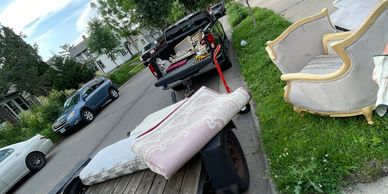 Furniture and rugs being moved on a residential street with trucks and trailers.