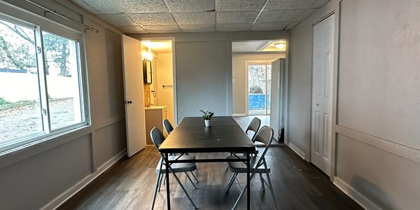 Minimalist dining area with a black table, four chairs, and a small plant centerpiece.