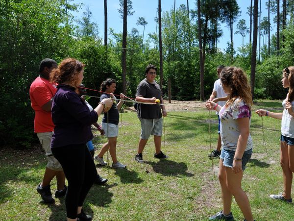 A group of people playing a team-building game outdoors.