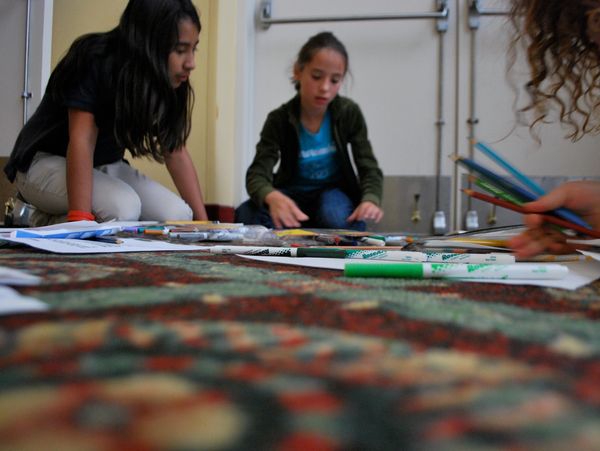 Children sitting on the floor, engaged in drawing and coloring activities.