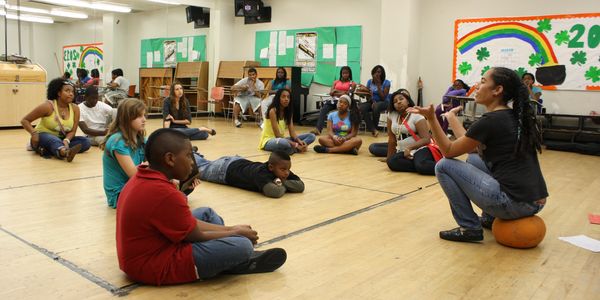 A group of children attentively listening to an instructor in a classroom setting.