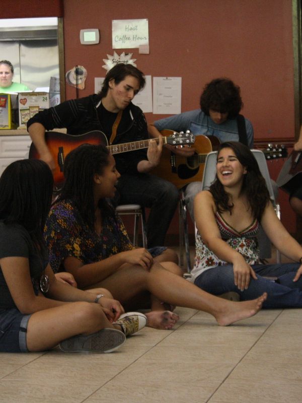 A group of young people enjoying music and laughter indoors.