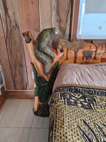 Wooden bedpost carved into a sloth and jungle scene.