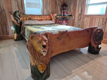 Rustic wooden bed with intricate animal carvings in a cozy room.