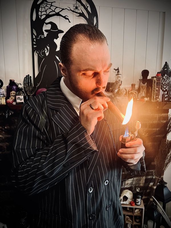 Man lighting a cigar in Halloween-themed room.