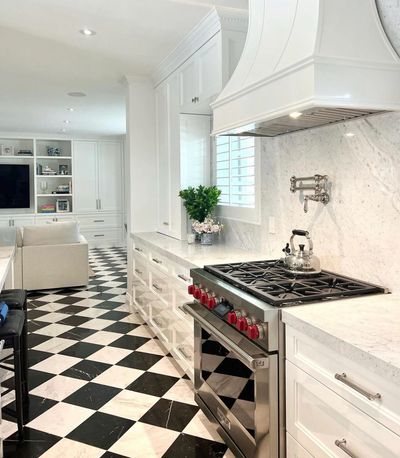 White kitchen with marble backsplash, professional range and checkerboard marble floor