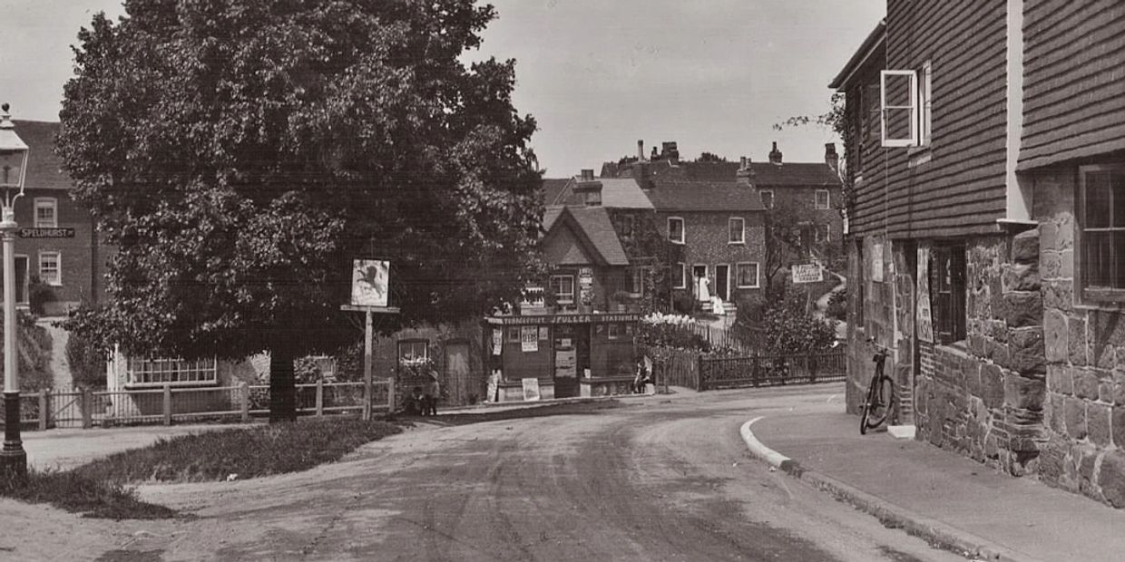 Vintage black and white street scene with shops, houses, and a bicycle.