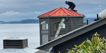 Worker fixing rooftop by a body of water.