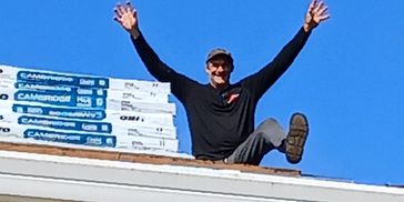 Man sitting on a roof with arms raised.