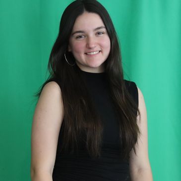 Young woman with long dark hair smiling against green background.