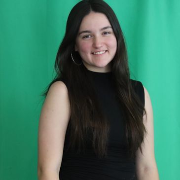 Young woman with long dark hair smiling against green background.