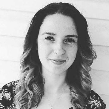 Black and white portrait of a smiling woman with curled hair.