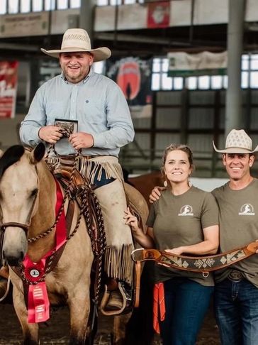 Teddy Franke atop a mustang horse holding the Winning buckle for the 100 day Mustang challenge.