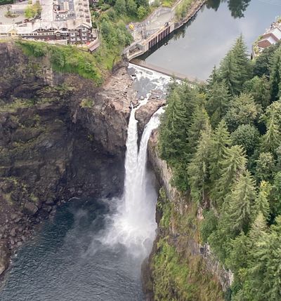 A waterfall flowing from a river into a pool surrounded by cliffs and trees.