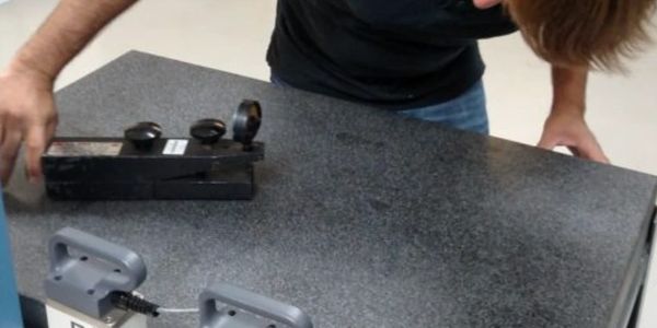 Person inspecting a black device on a table.