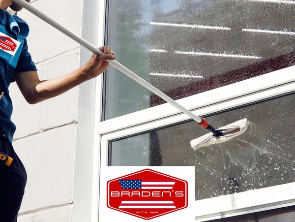 Professional cleaning a large window with a squeegee.