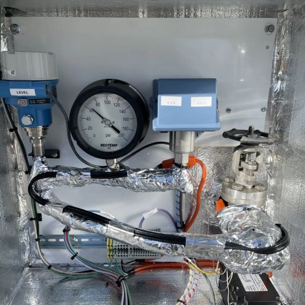 Pressure gauge and control instruments inside a metallic enclosure.