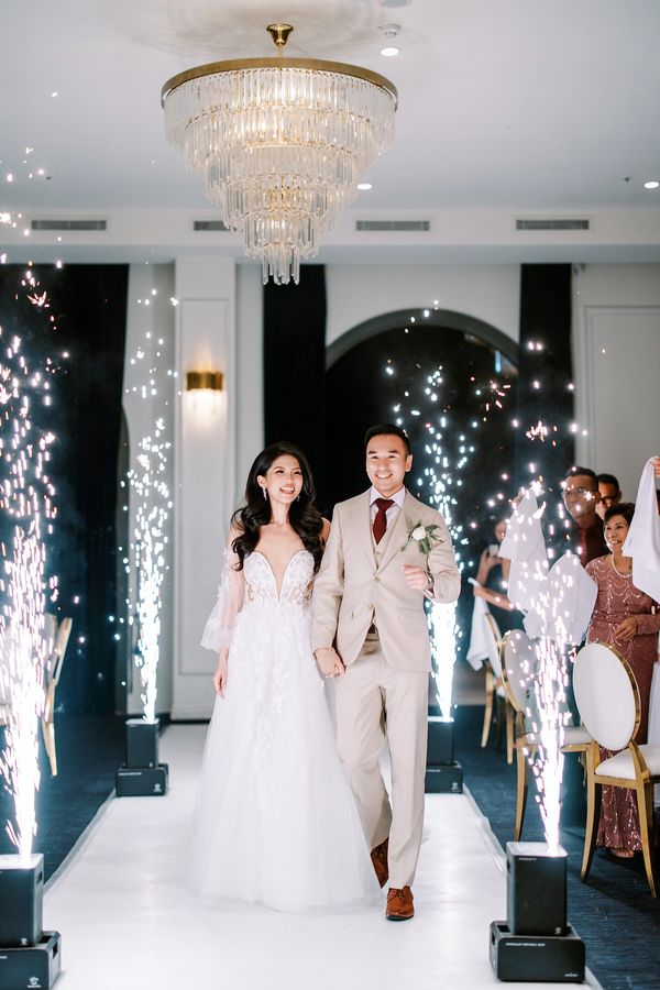 Bride and groom joyfully walking down the aisle with sparkling fireworks around.