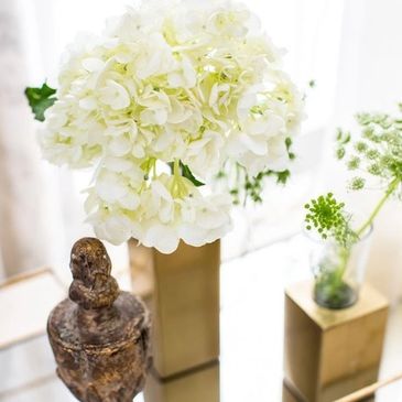 White hydrangea arrangement in gold square vases.