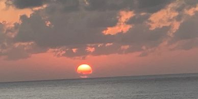 Sunset over the ocean with clouds reflecting warm colors.