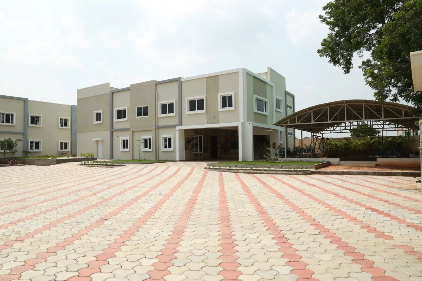 Modern residential building with tiled courtyard and shaded play area.