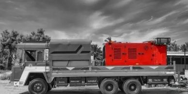 A red generator on a gray flatbed truck.