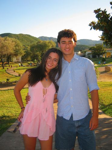 Young couple posing outdoors on a sunny day with hills in the background.