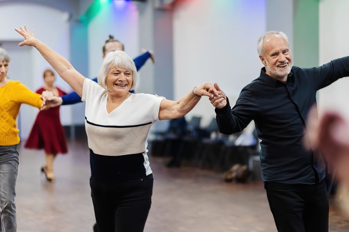 Happy older couple, smiling, holding hands and learning to dance in Cosby.