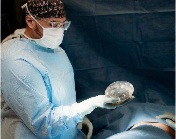 Surgeon holding a breast implant in operating room.