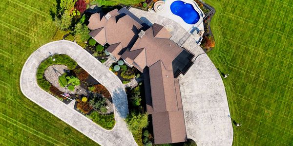 an overhead view of a large house with a curved driveway and green lawn