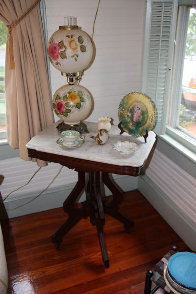 Antique wooden table with floral lamp and decorative porcelain items.