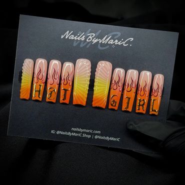 Gradient flame nails spelling 'HOT GIRL' with detailed designs on a black card.