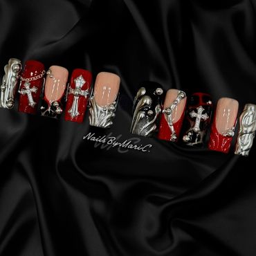 Intricate gothic nail art with crosses and metallic embellishments on red and black base.