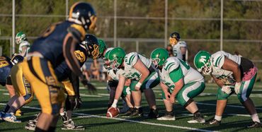 High school football players lined up for a play on a sunny day.