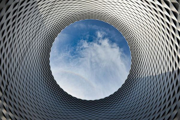 View of blue sky through a circular architectural structure.
