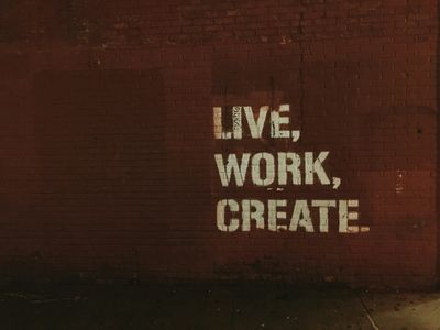 Motivational graffiti on a brick wall: Live, Work, Create.