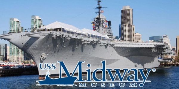 USS Midway Museum aircraft carrier docked in a city harbor.