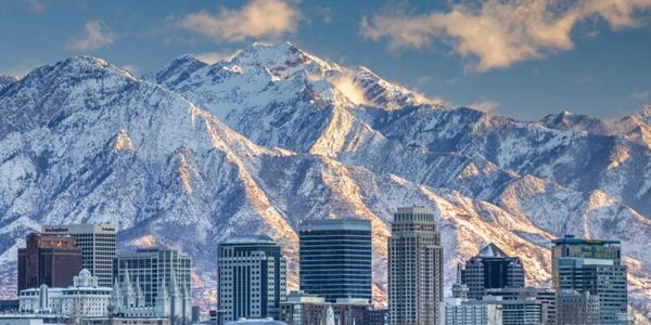 City skyline with snow-covered mountains in the background.