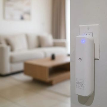 A white electronic device plugged into a wall outlet in a living room.
