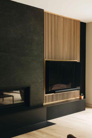 Modern black and wood TV wall with fireplace.