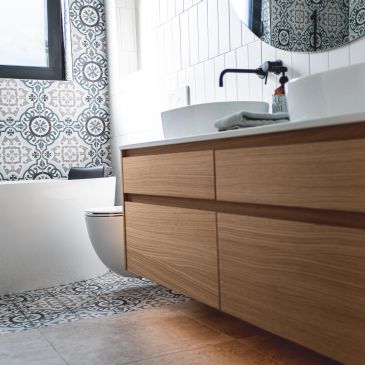 Salle de bain moderne avec meuble en bois et carrelage motifs.