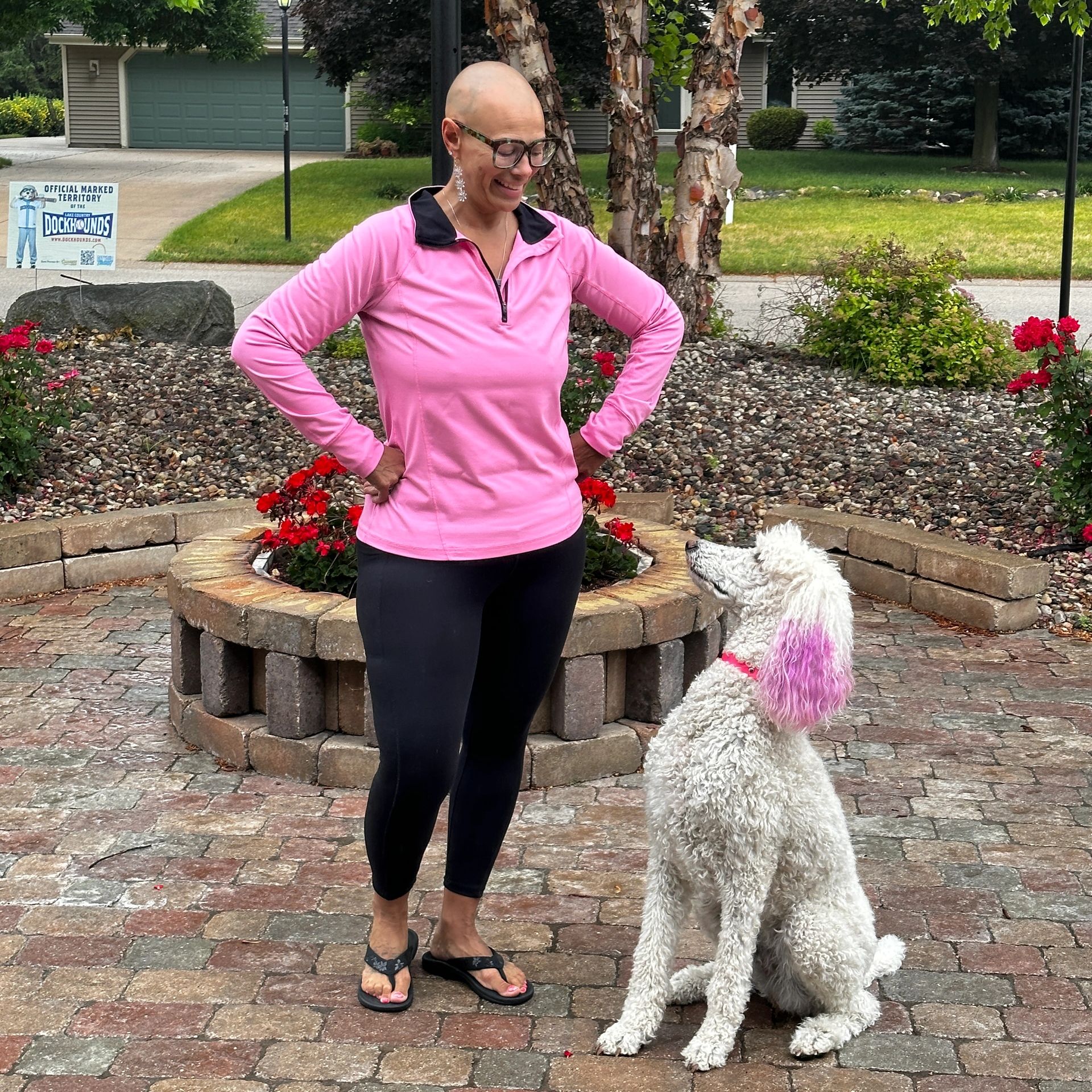 Woman in pink top with a dog having pink-dyed ears.