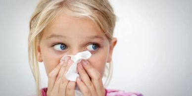 Young girl blowing her nose