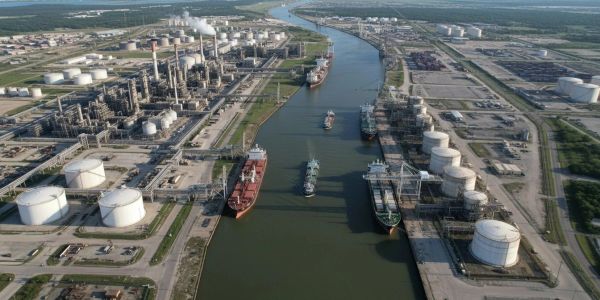 Aerial view of an industrial port with ships and storage tanks.
