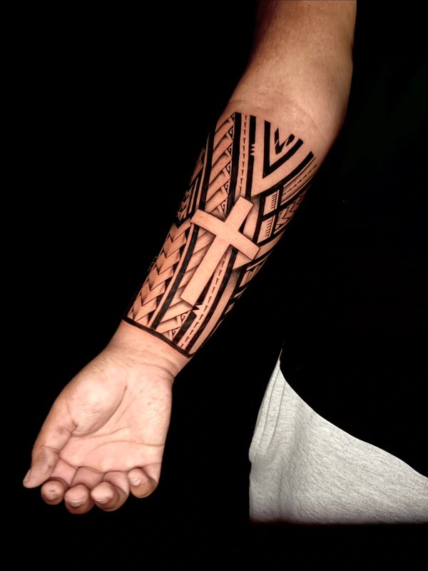 Tribal forearm tattoo with a prominent cross design.