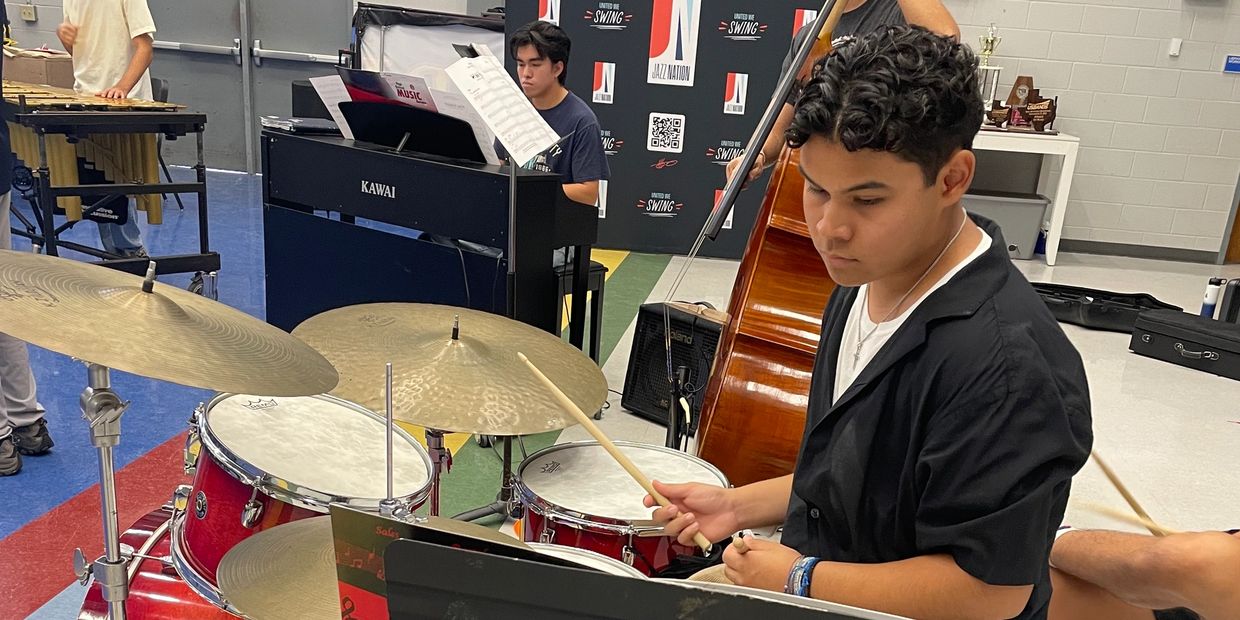 Teen boy playing drums in a music room.