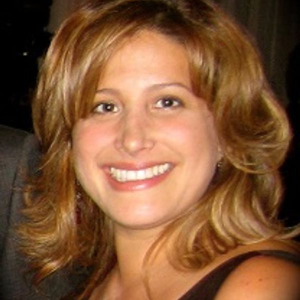 A smiling woman with shoulder-length blonde hair and a dark dress.