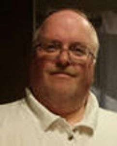 Smiling middle-aged man wearing glasses and a white shirt.