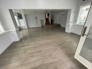Empty room with wooden flooring and stairs leading up.