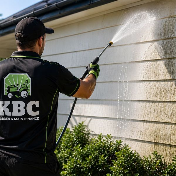 Man power washing a house exterior with visible dirt removal.